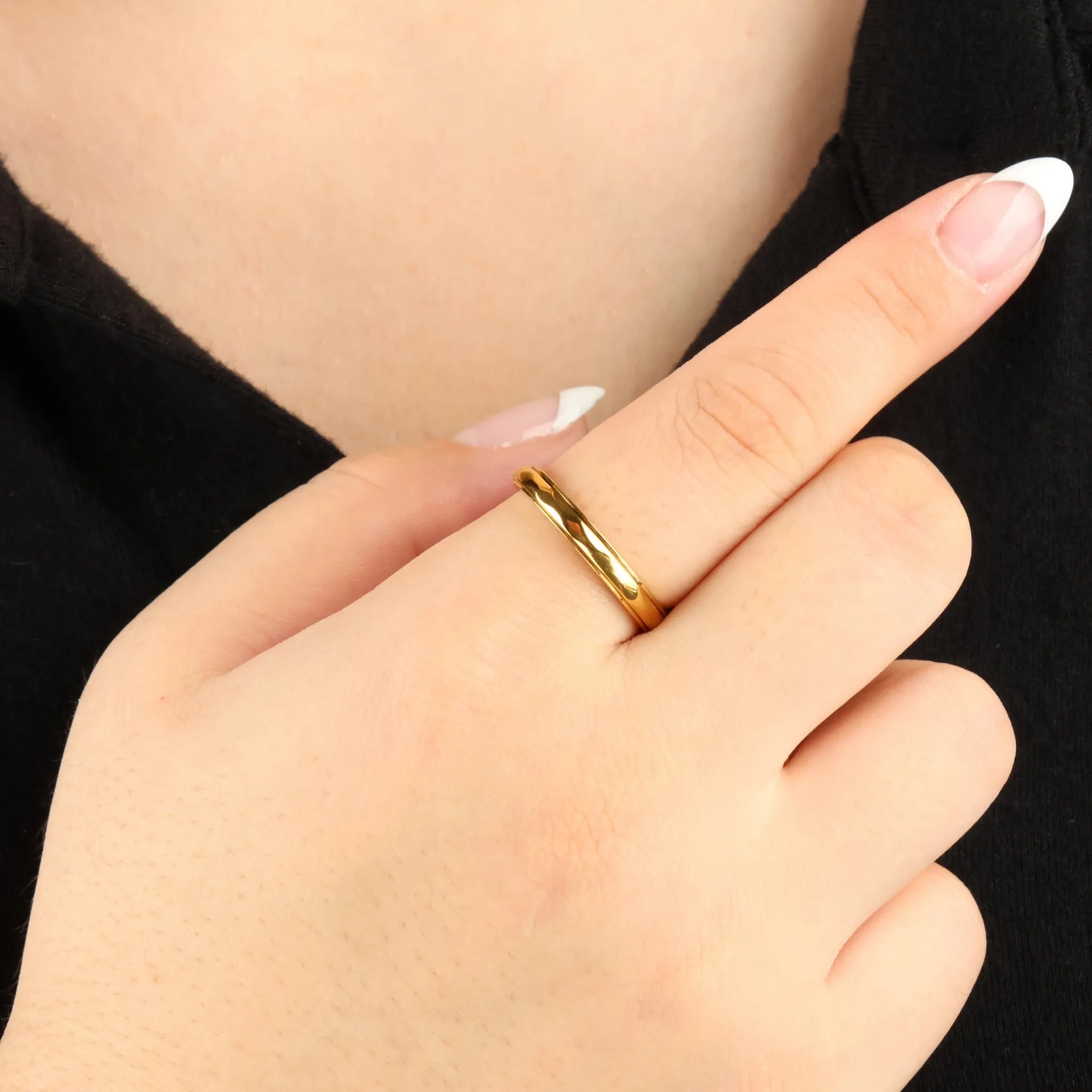 Gouden Amara anxiety ring met golvend design gedragen door vrouw met zwart shirt – Luminora