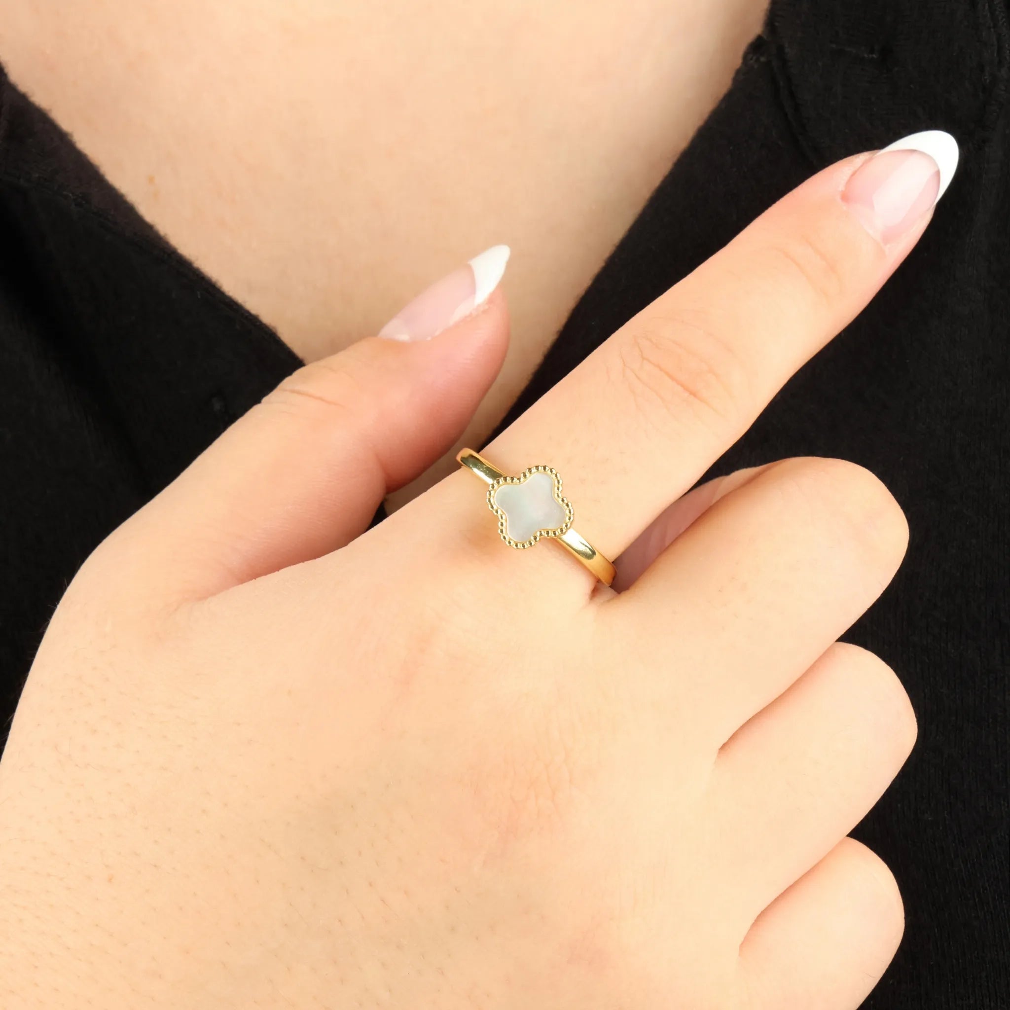 Clover anxiety ring in goud gedragen aan hand bij zwarte blouse, glanzend stainless steel – Luminora