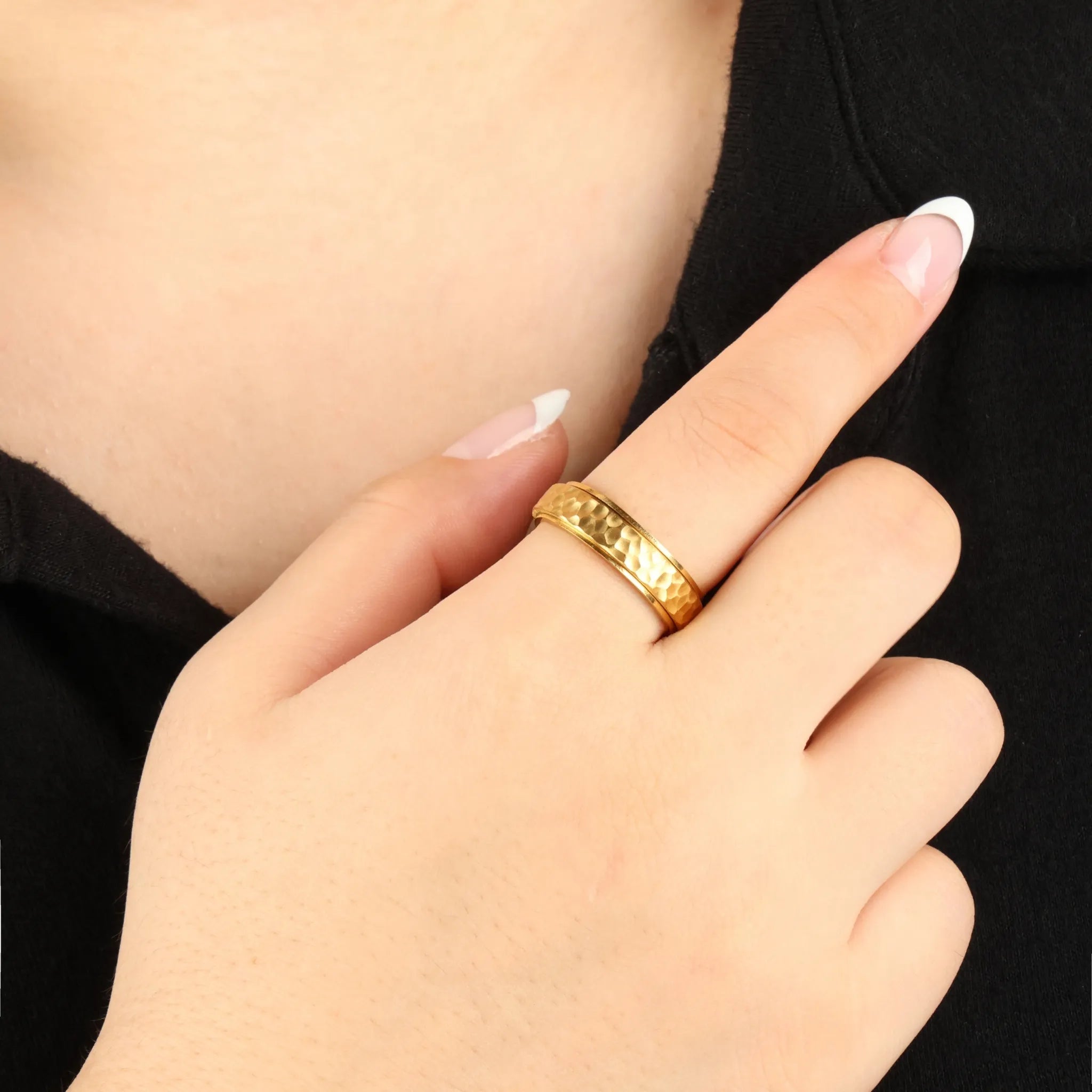 Gouden Echo anxiety ring met gehamerde textuur gedragen bij zwarte outfit – Luminora