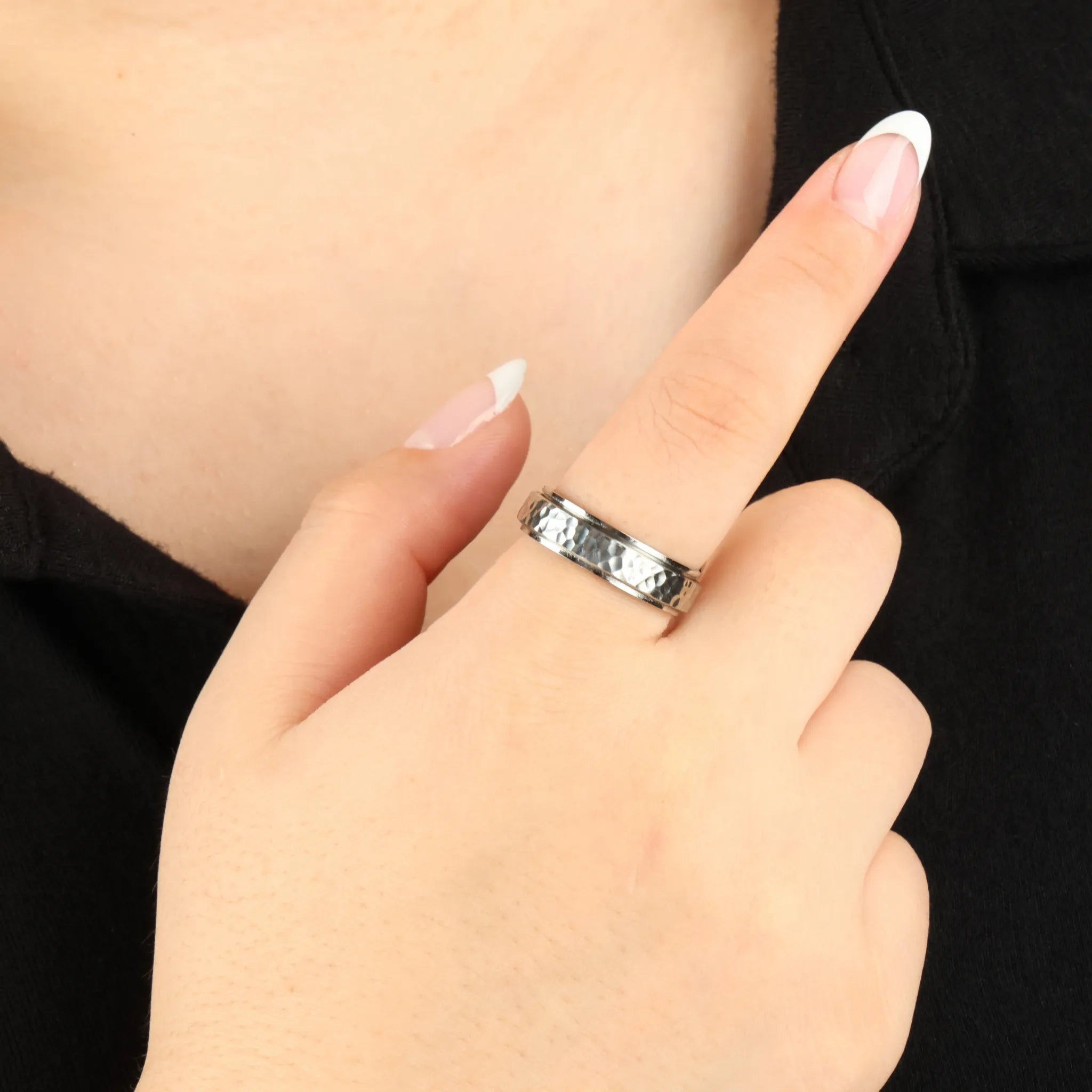 Echo anxiety ring in zilver met gehamerd patroon gedragen aan hand bij zwarte blouse – Luminora
