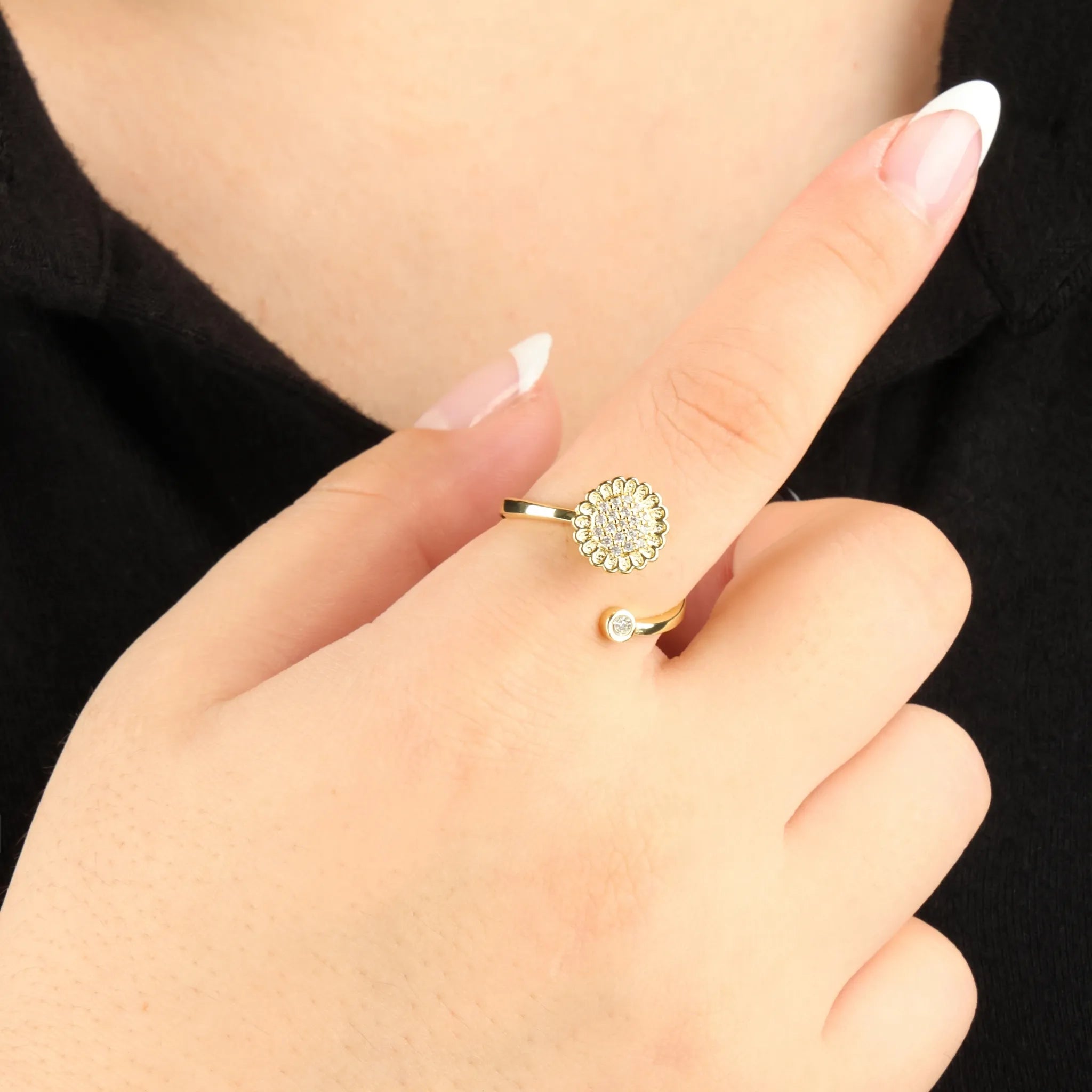 Goudkleurige verstelbare Lotus anxiety ring gedragen bij zwarte blouse, bloemvormige steen en kristal – Luminora