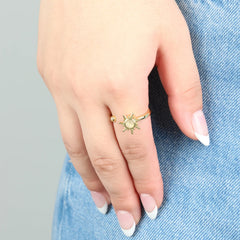Gouden Solar anxiety ring met zonvormig design, gedragen op jeans – moderne verstelbare ring die kalmte en balans brengt