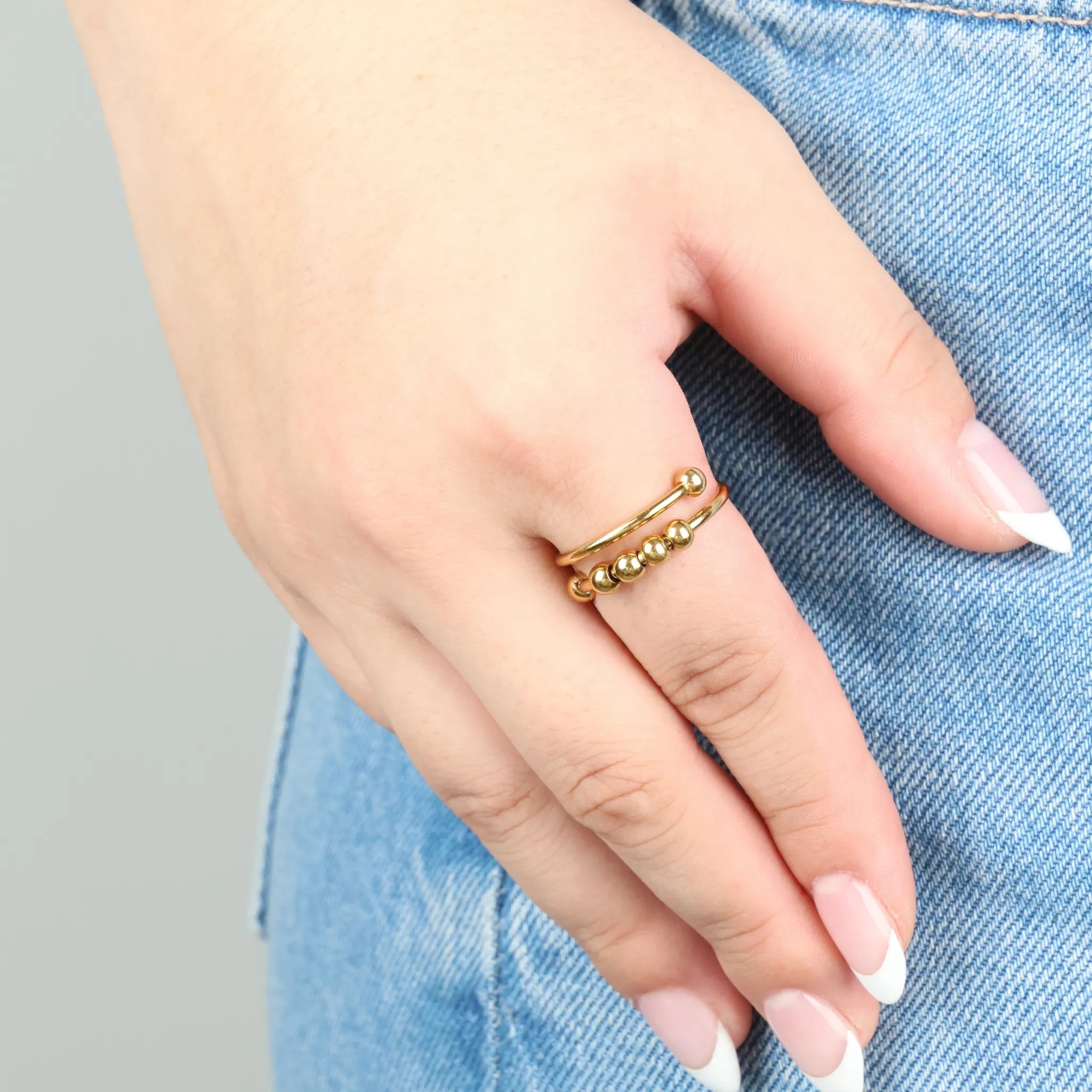 Gouden Wave Bead anxiety ring met minimalistisch design, gedragen op jeans – ring die helpt bij stressvermindering en rust