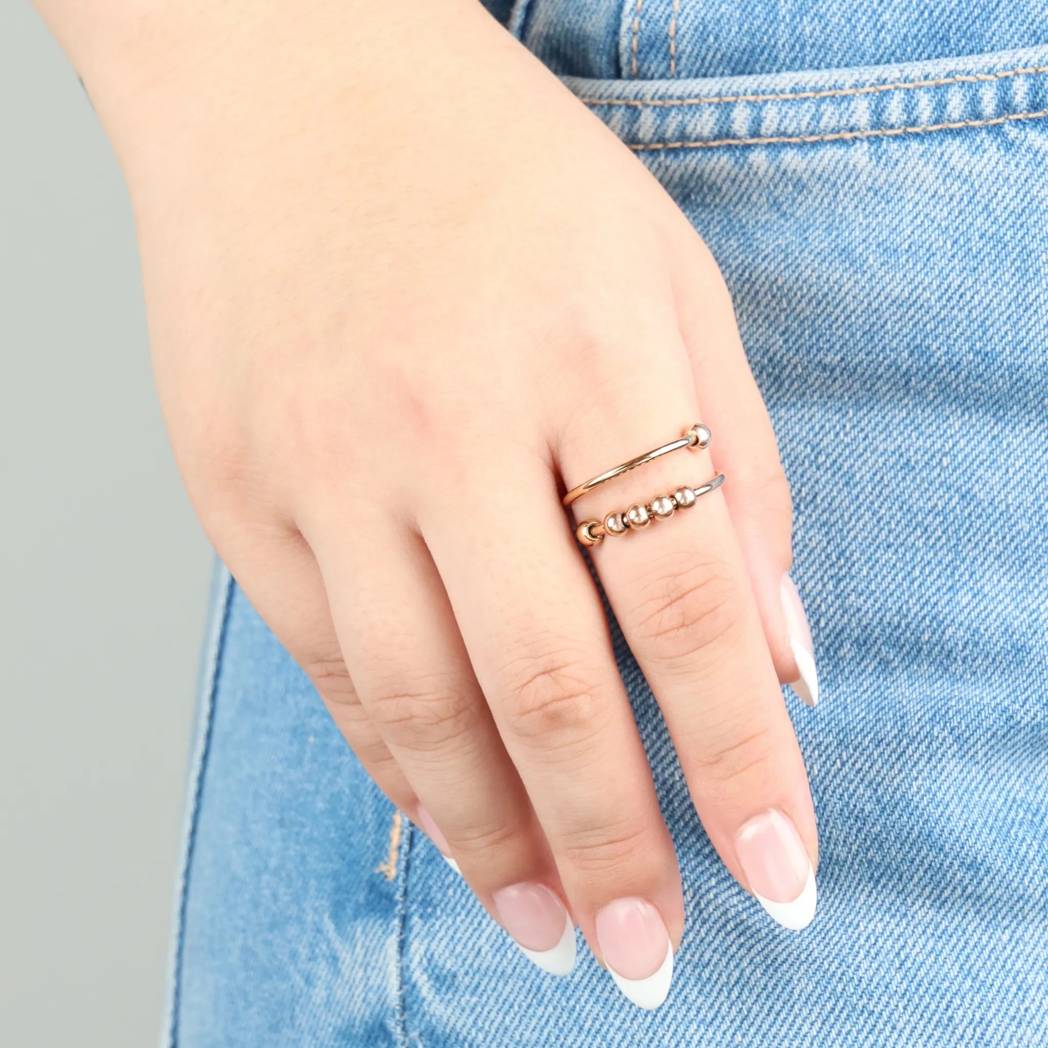 Roségouden Wave Bead anxiety ring met glanzende kralen, gedragen op jeans – verstelbare ring die helpt spanning te verminderen