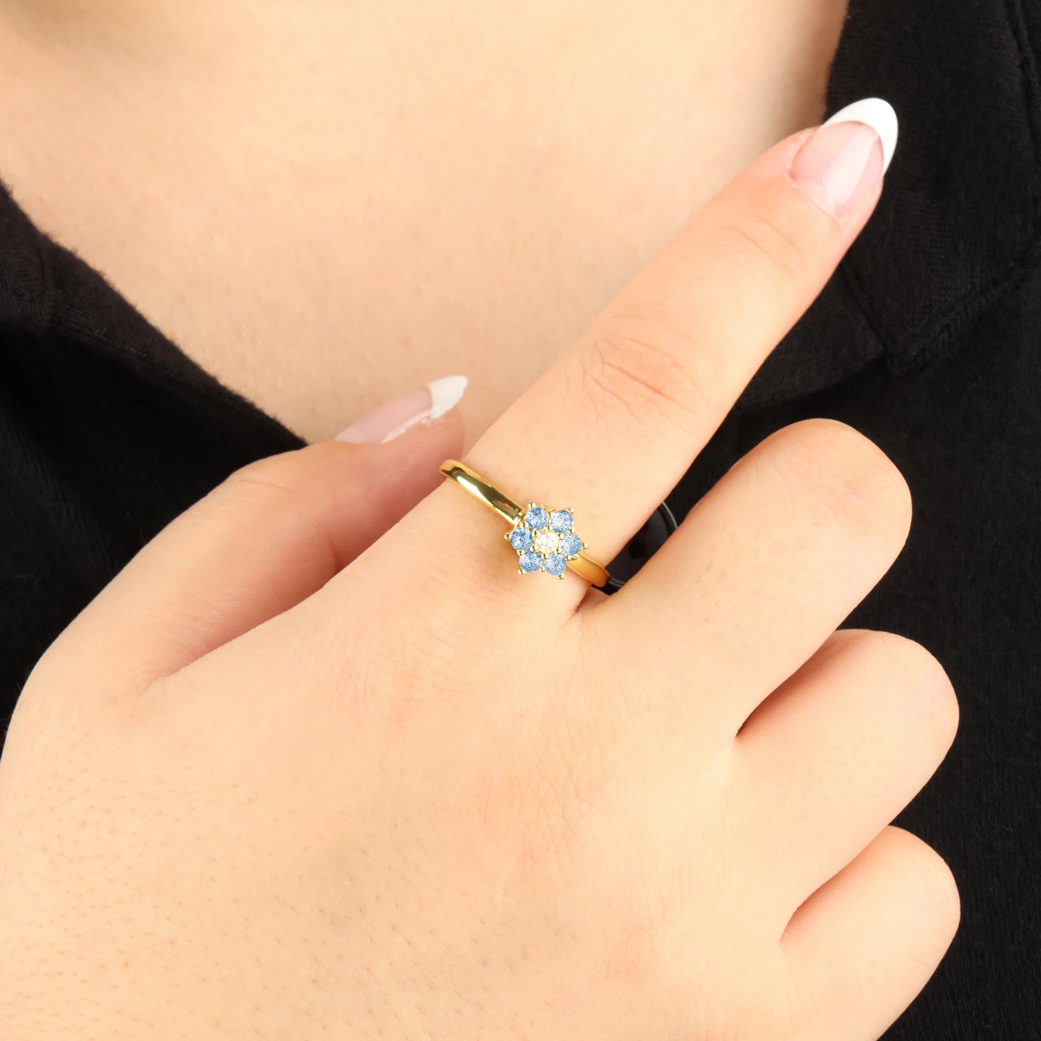 Gouden Aqua anxiety ring met een draaiende blauwe kristallen bloem, gedragen bij een zwart shirt.