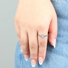 Close-up van de zilveren Aqua stress ring met blauwe steentjes gedragen op een spijkerbroek.