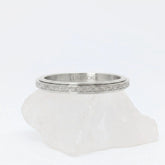 Zilveren Astra anxiety ring ontworpen als subtiele fidget ring, geplaatst op een witte kwartssteen.