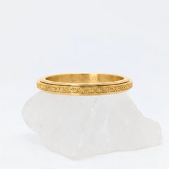 Gouden Astra fidget ring met glinsterende textuur, gepresenteerd op een witte kristallen steen.