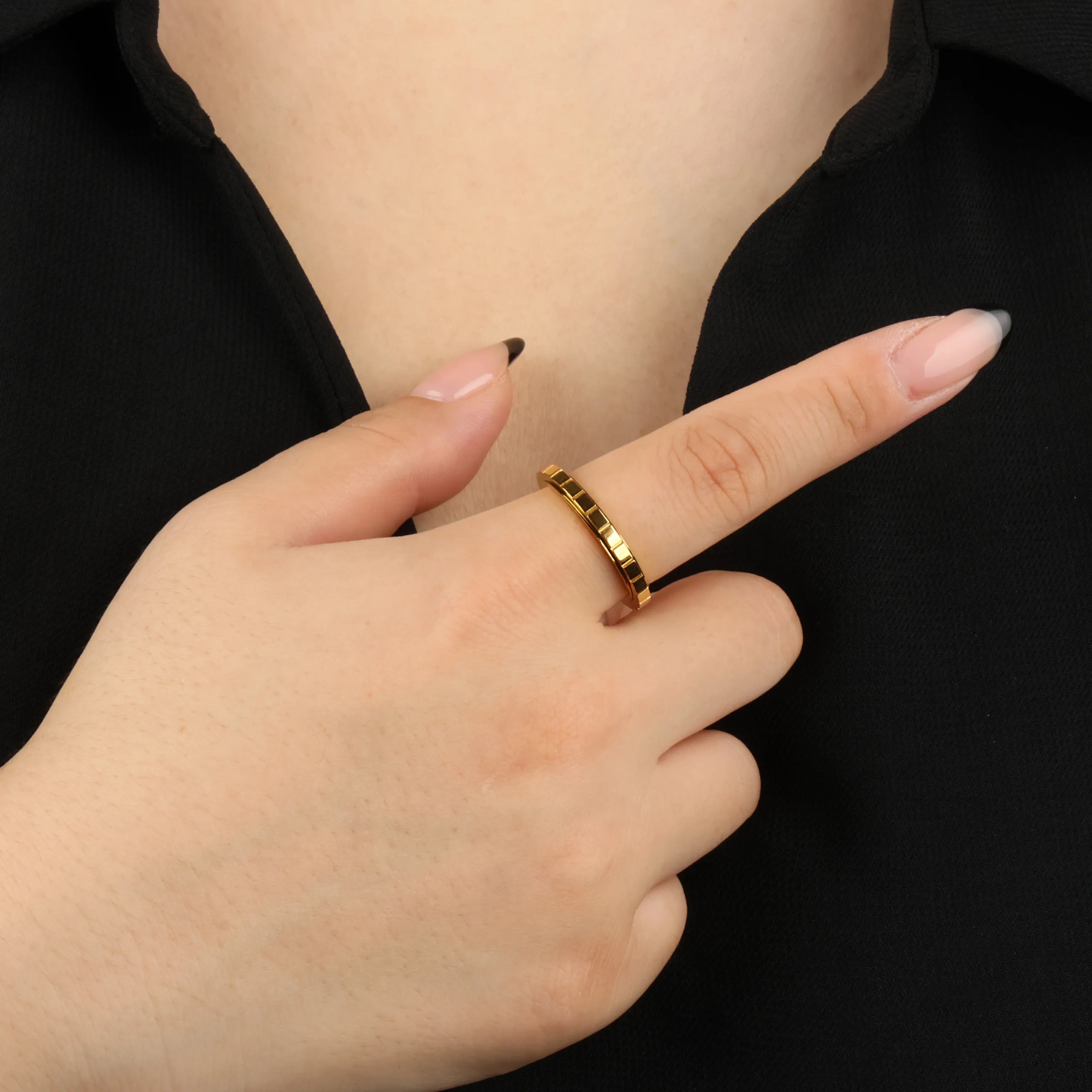 Gouden Axis anxiety ring met strak groevenpatroon, gedragen aan hand voor zwart shirt – Luminora