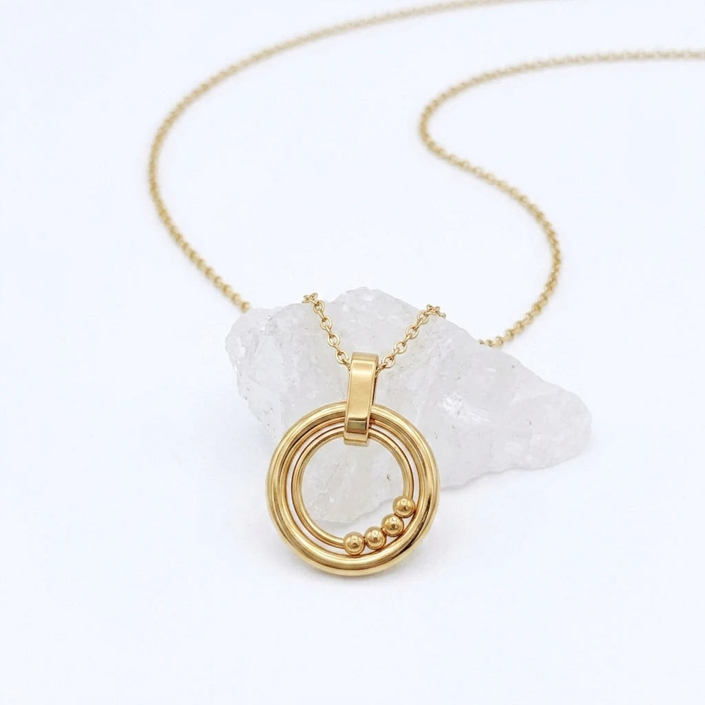 Bead Ketting in goud van RVS met beweegbare kralen op een witte steen – stijlvolle fidget ketting voor rust en ontspanning.