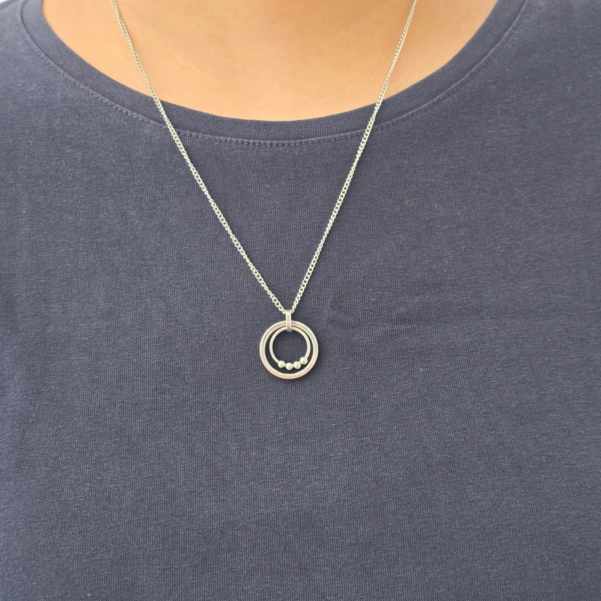 Zilveren Bead Ketting van RVS met beweegbare kralen gedragen om de hals bij een blauw shirt – subtiele fidget ketting voor dagelijks gebruik.