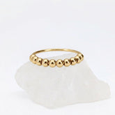 Gouden Classic Bead fidget ring van RVS met los te bewegen kralen, elegant gepresenteerd op een witte steen.