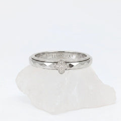 Zilveren Clover anxiety ring met een glanzend klavertje vier bezet met steentjes en een geometrisch gefacetteerde band, gepresenteerd op een witte steen.