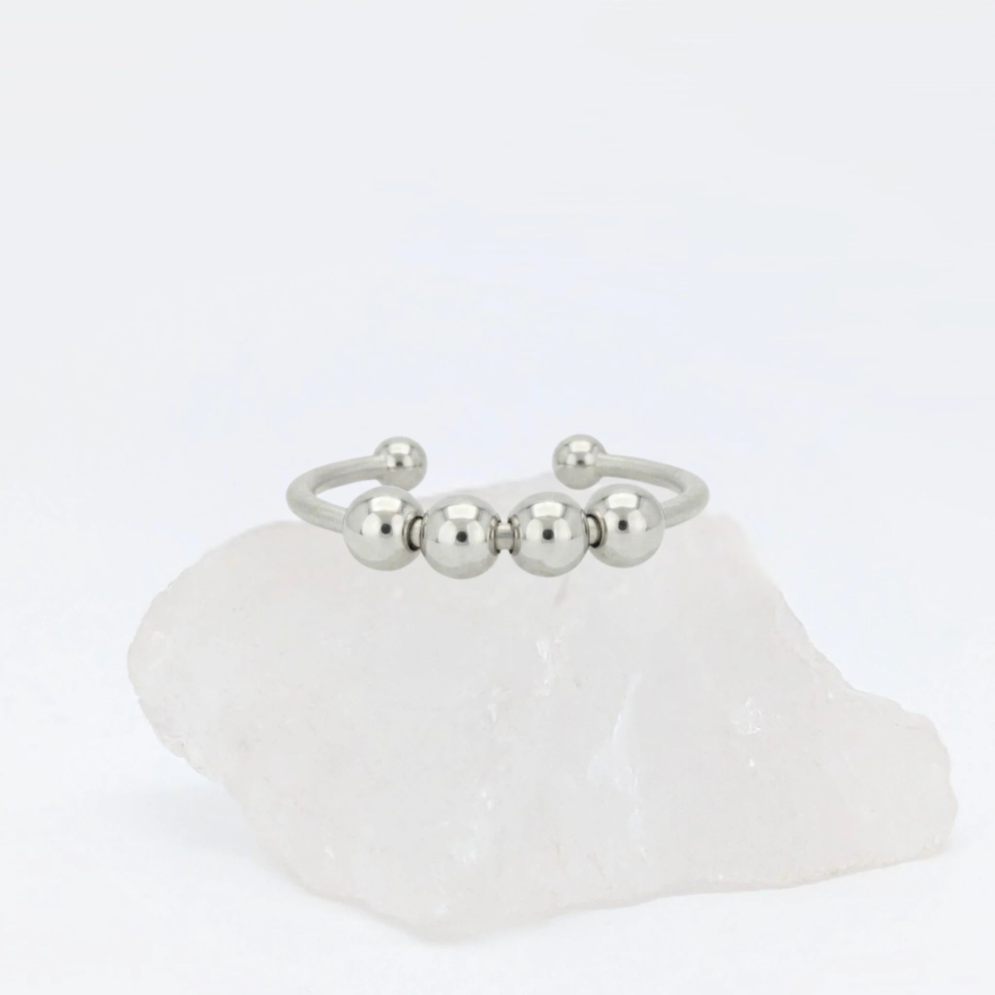 Zilveren Core Bead anxiety ring ontworpen als subtiele fidget ring, geplaatst op een witte kwartssteen.