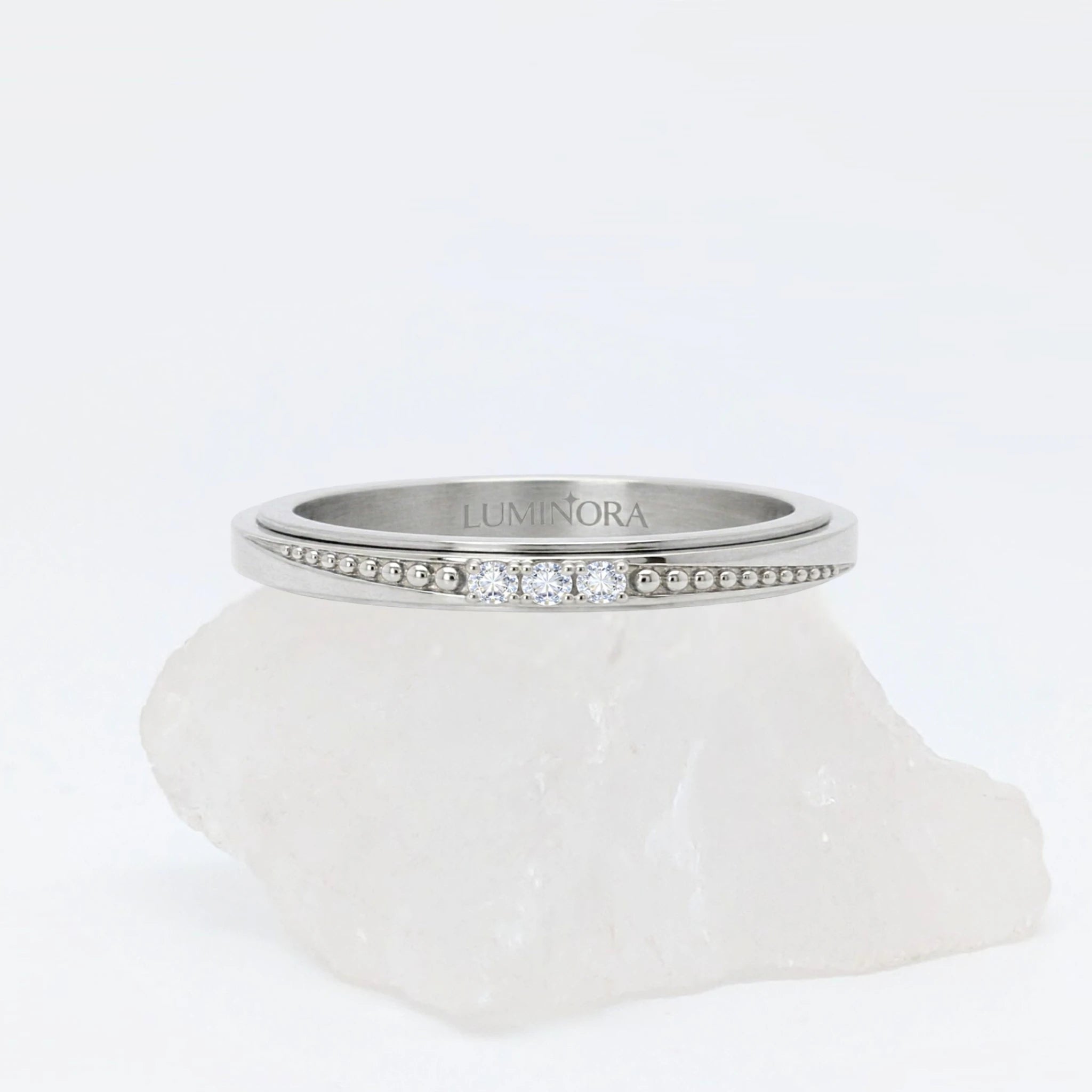 Zilveren Elara anxiety ring ontworpen als elegante fidget ring, geplaatst op een witte kwartssteen.