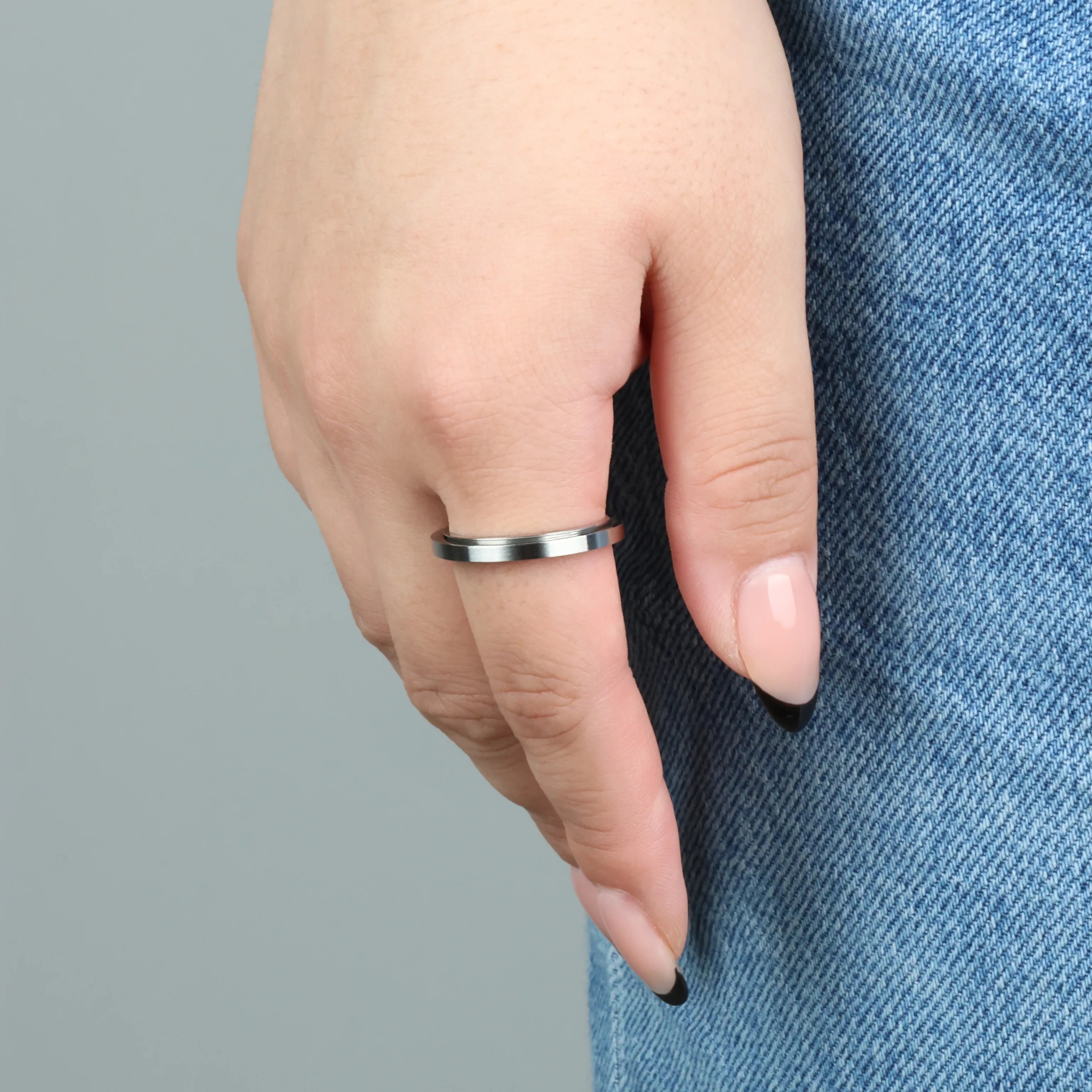Vrouw draagt zilveren Essence anxiety ring, dun en stijlvol bij spijkerbroek – Luminora