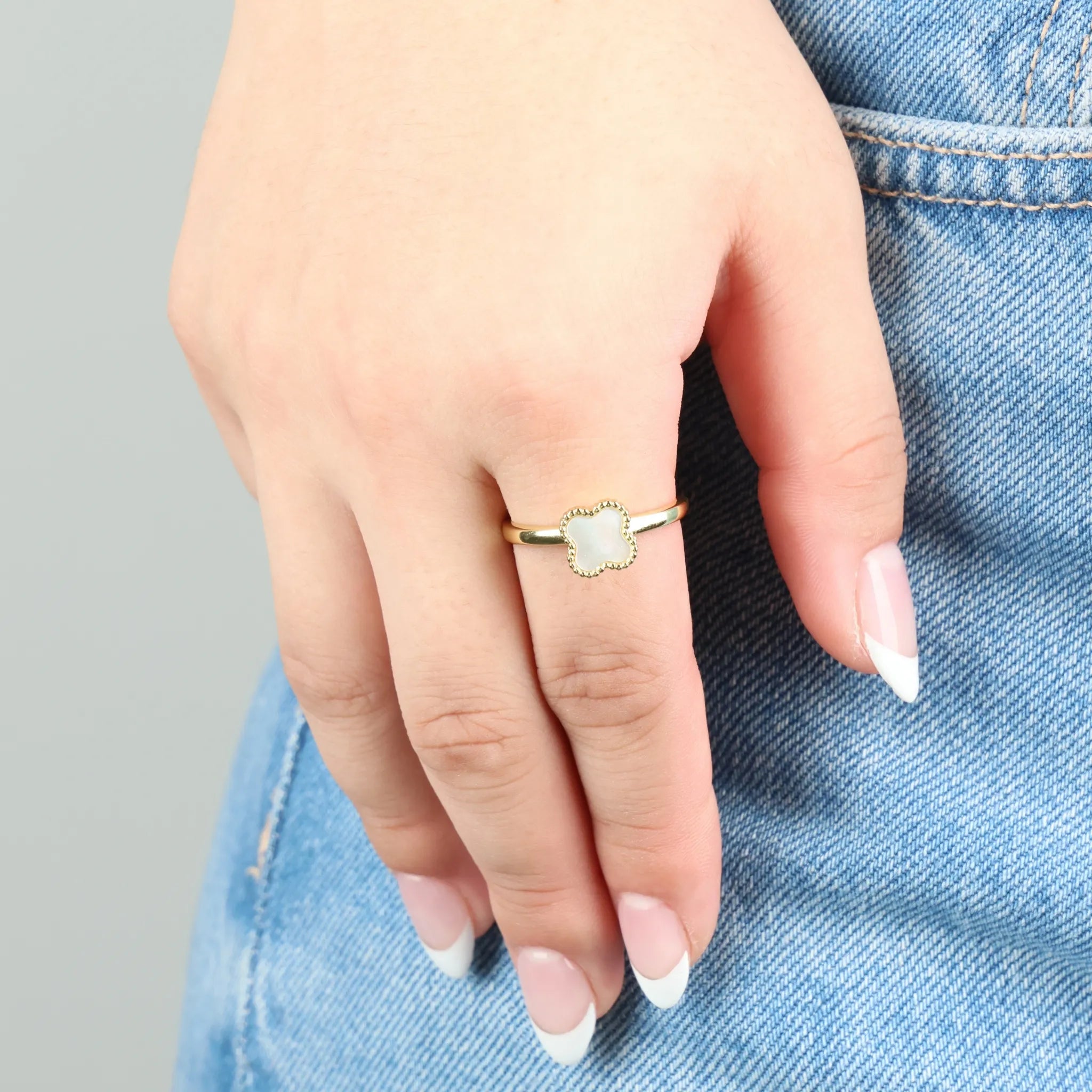 Gouden Clover fidget ring gedragen aan hand op denim jeans, elegant en stijlvol ontwerp
