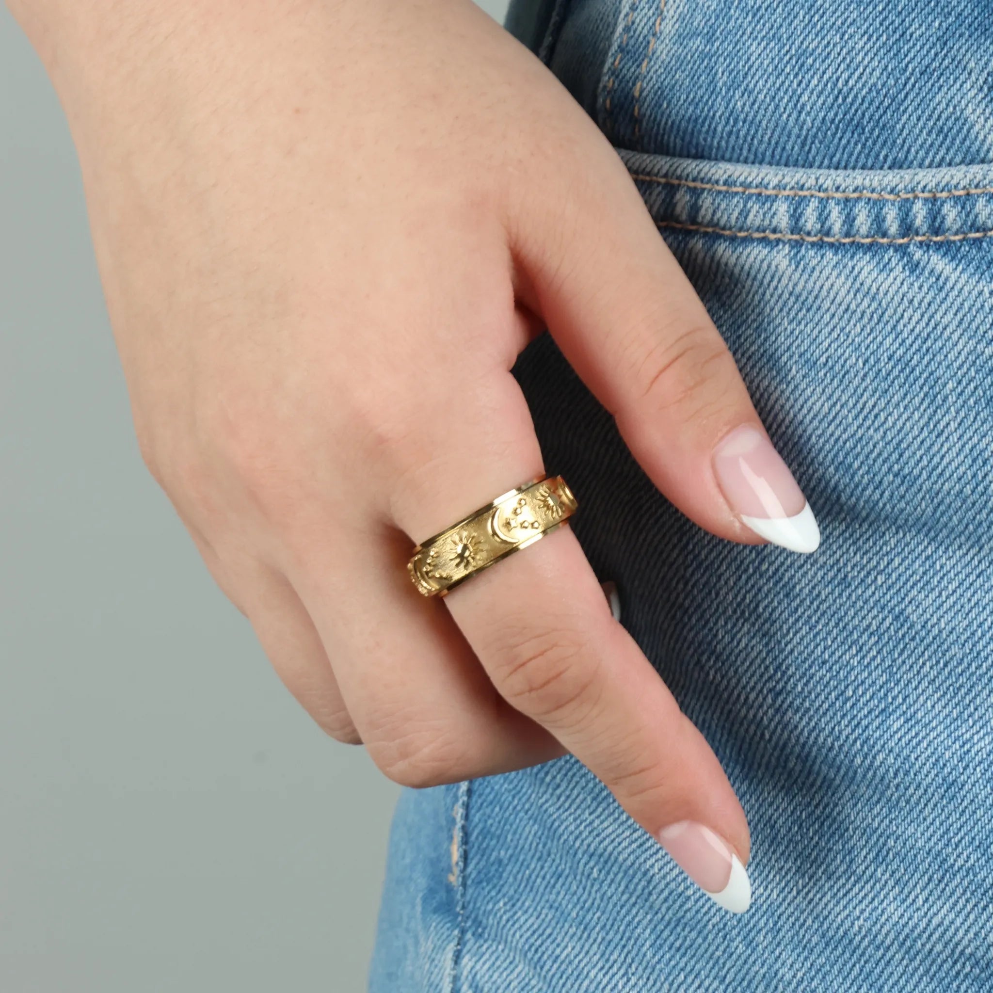 Gouden Cosmic fidget ring gedragen aan hand op jeans, stijlvolle look met subtiel kosmisch patroon