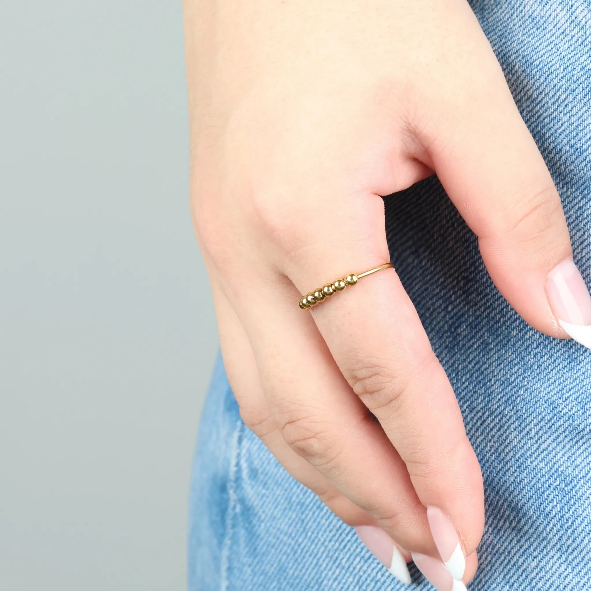 Gouden Bead fidget ring gedragen aan wijsinger in zacht daglicht, subtiele glans en elegante uitstraling