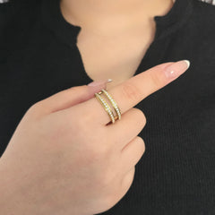 Detailopname van een gouden fidget ring met twee rijen kristallen aan de wijsvinger van een model met een zwart topje.