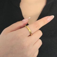 Detailopname van een minimalistische gouden Prism fidget ring met een geometrische afwerking, gedragen aan de wijsvinger door een model in een zwart topje.