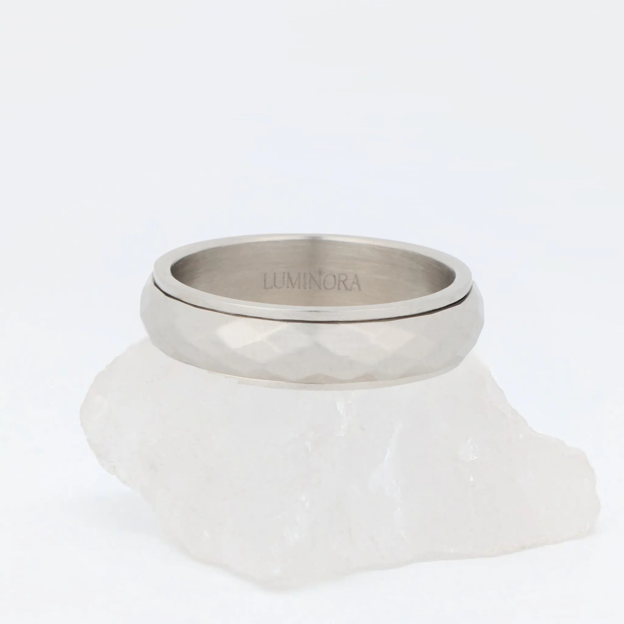 Zilveren Nova fidget ring van stainless steel met hamerslag-afwerking, studio close-up op witte steen – Luminora