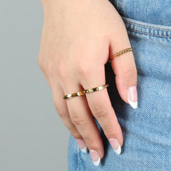 Drie fidget ringen uit de Dawn Bundel gedragen aan hand op jeans, goudkleurig edelstaal met subtiele glans