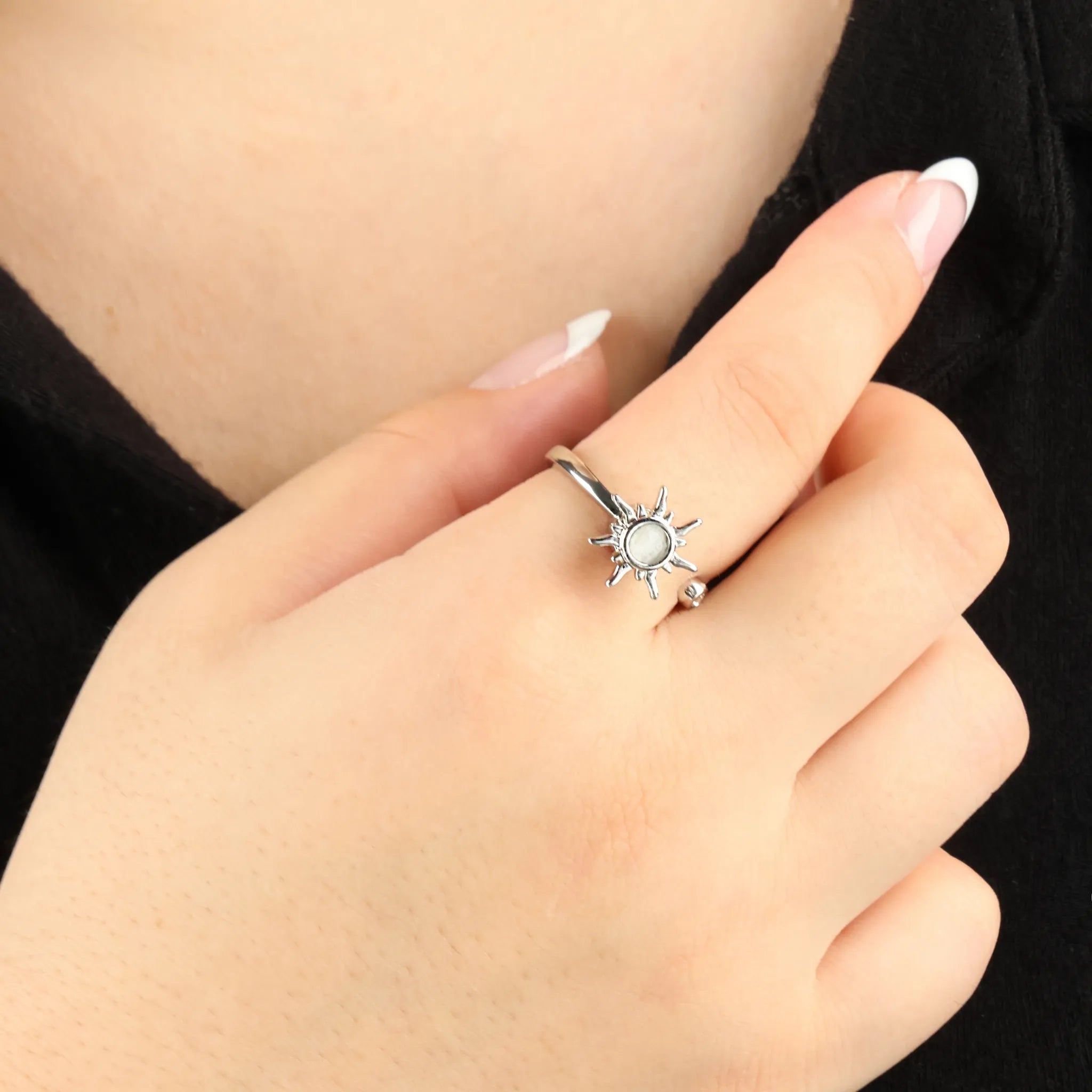 Zilverkleurige Solar fidget ring met zonachtig design, gedragen bij zwarte outfit – stijlvolle wellness ring voor ontspanning