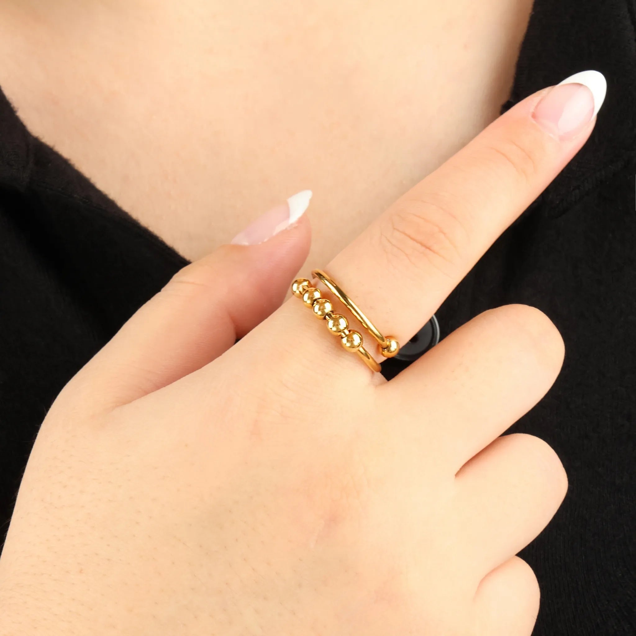 Wave Bead fidget ring in goud met glanzende kralen, gedragen bij zwarte top – stijlvolle ring die helpt ontspannen bij onrust