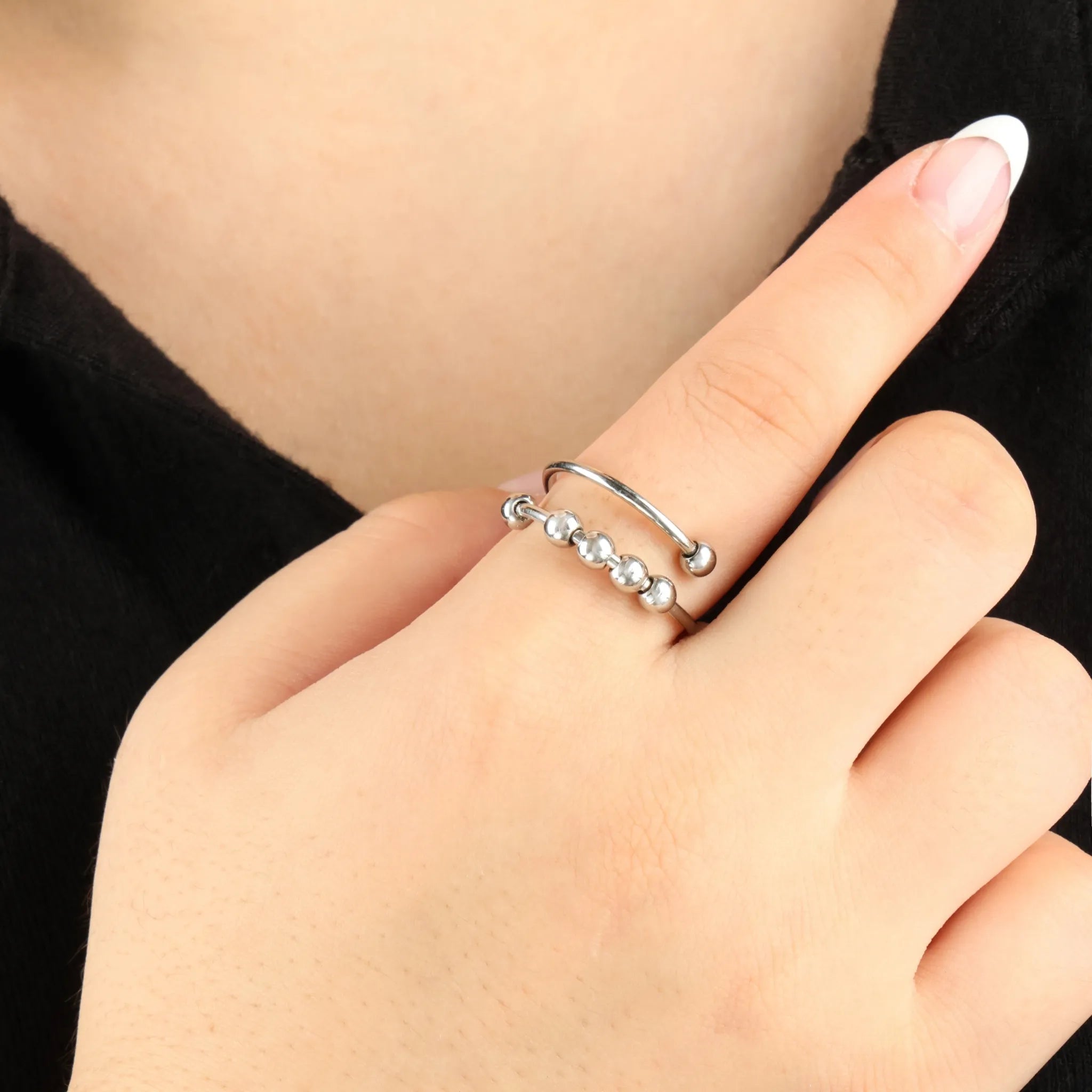Wave Bead fidget ring in zilver, gedragen bij zwarte outfit – stijlvolle wellness ring met draaiende kralen voor ontspanning