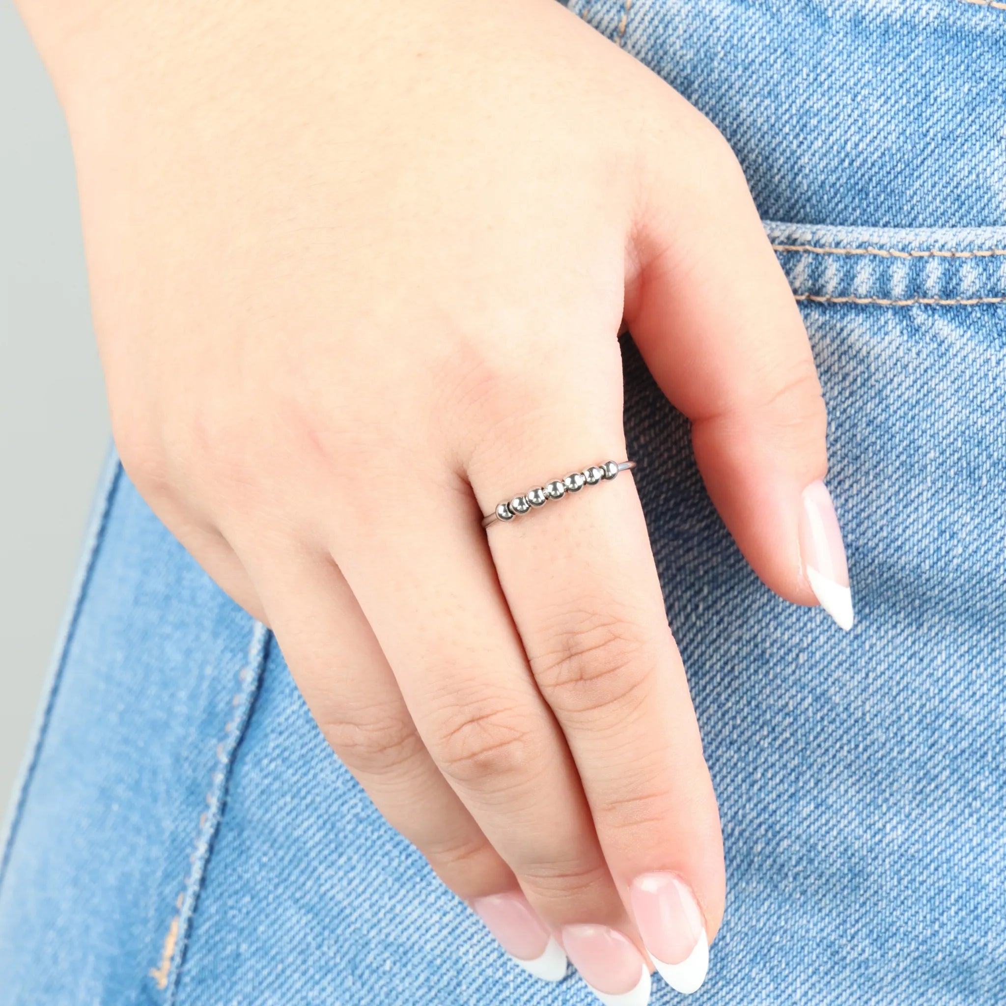 Zilveren fidget ring met bolvormige kralen aan wijsvinger bij natuurlijk licht