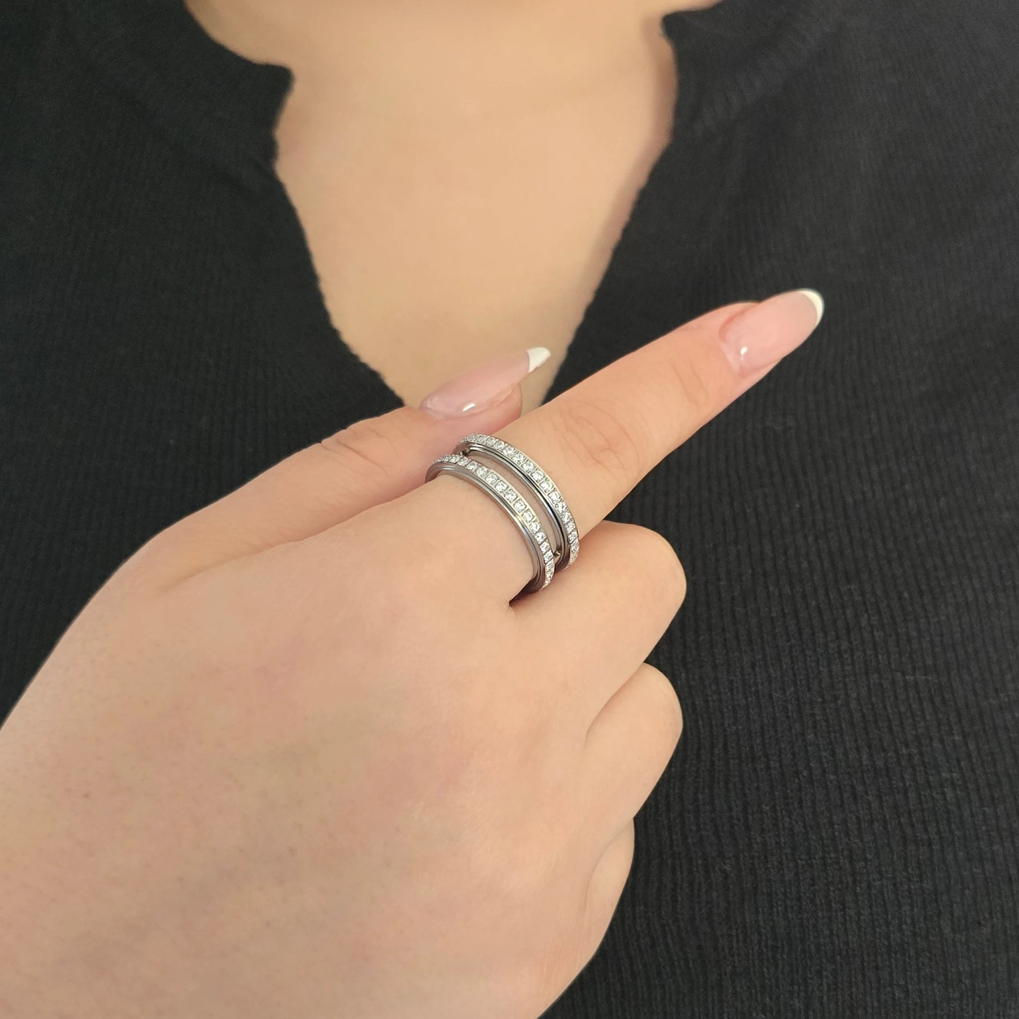 Elegante zilveren fidget ring met een dubbele rij fonkelende steentjes, gedragen door een model met een chique zwart topje.