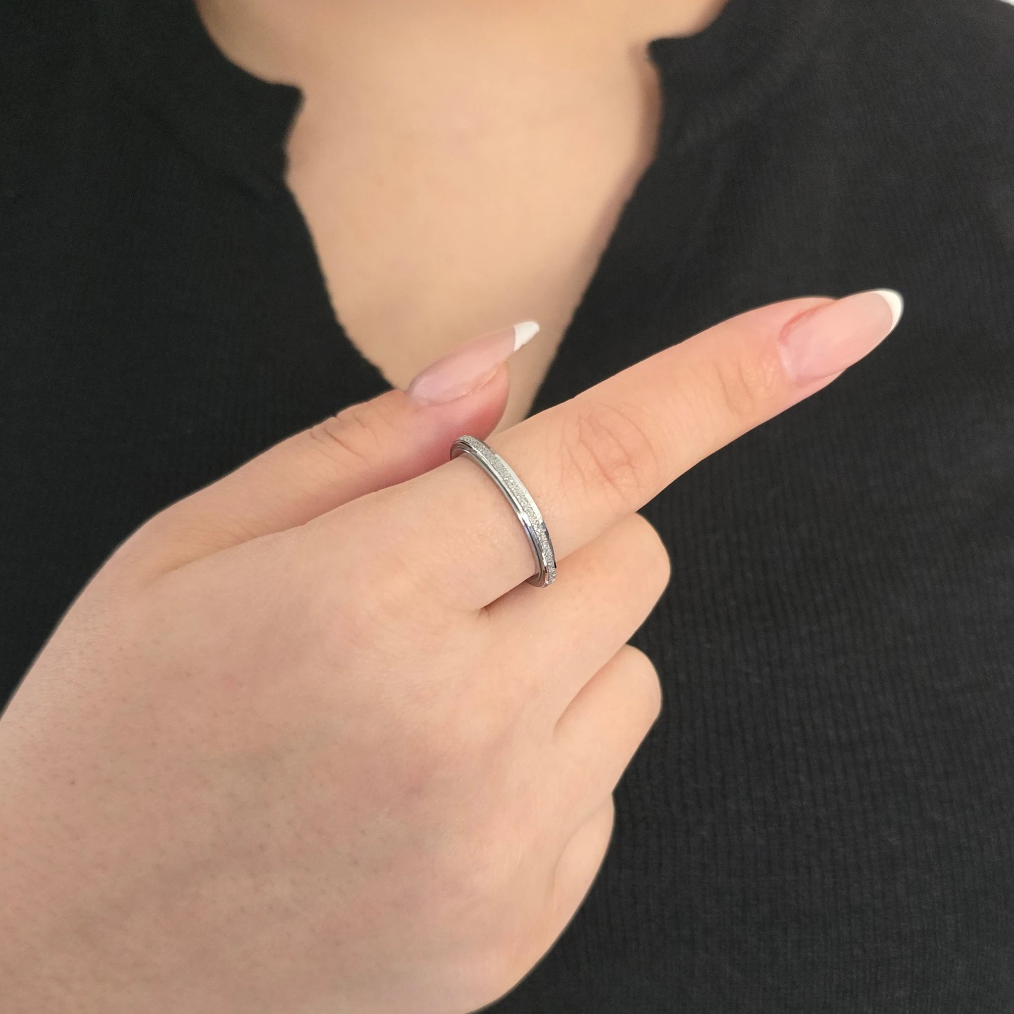 Elegante zilveren fidget ring met draaibare band, gedragen door een model met een zwart topje.