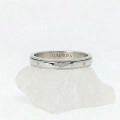 Zilveren Fortuna fidget ring van RVS met een roterende band voorzien van gegraveerd klaver patroon, gepresenteerd op een witte steen