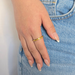 Hand van een vrouw in een blauwe jeans met een draagbare gouden anti-stress ring aan haar vinger.