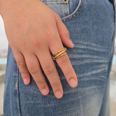 Hand van een vrouw met de gouden Neo anxiety ring met roterend middendeel en steentjes, rustend op een casual blauwe jeans.