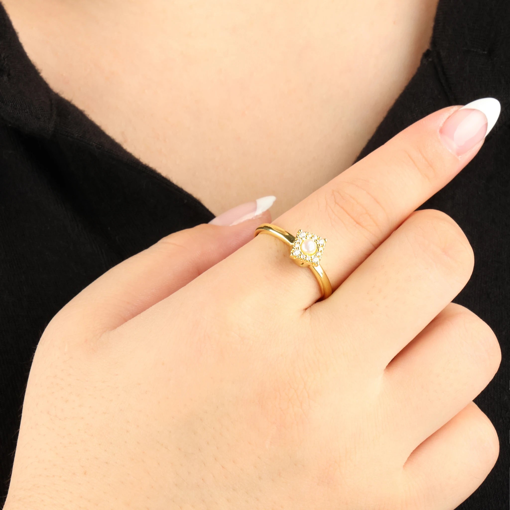 Gouden Halo anti-anxiety ring met een draaiend vierkant kopje ingezet met steentjes, gedragen bij een zwart shirt.