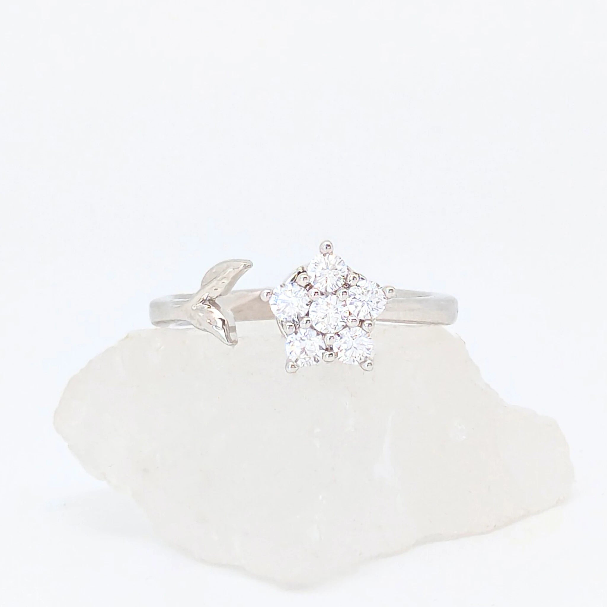 Zilveren Iris fidget ring met een glanzende bloem van kristallen en een verfijnd zilveren blaadje, liggend op een witte steen.