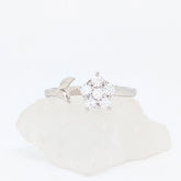 Zilveren Iris fidget ring met een glanzende bloem van kristallen en een verfijnd zilveren blaadje, liggend op een witte steen.