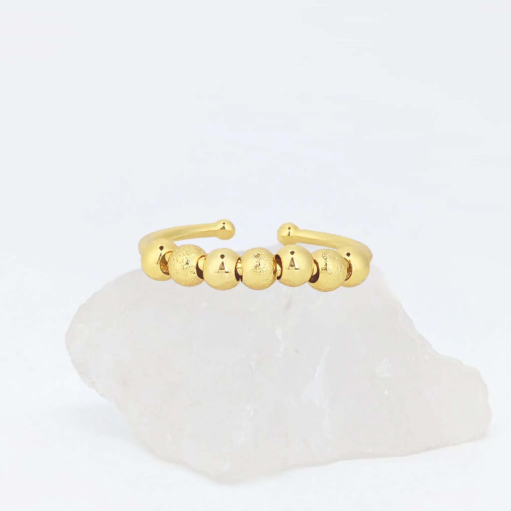 Gouden Ivy Bead fidget ring met glanzende en geribbelde kralen op witte steen – verstelbaar design