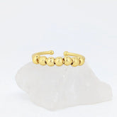 Gouden Ivy Bead fidget ring met glanzende en geribbelde kralen op witte steen – verstelbaar design