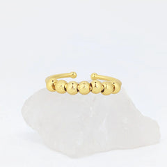 Gouden Ivy Bead fidget ring met glanzende en geribbelde kralen op witte steen – verstelbaar design