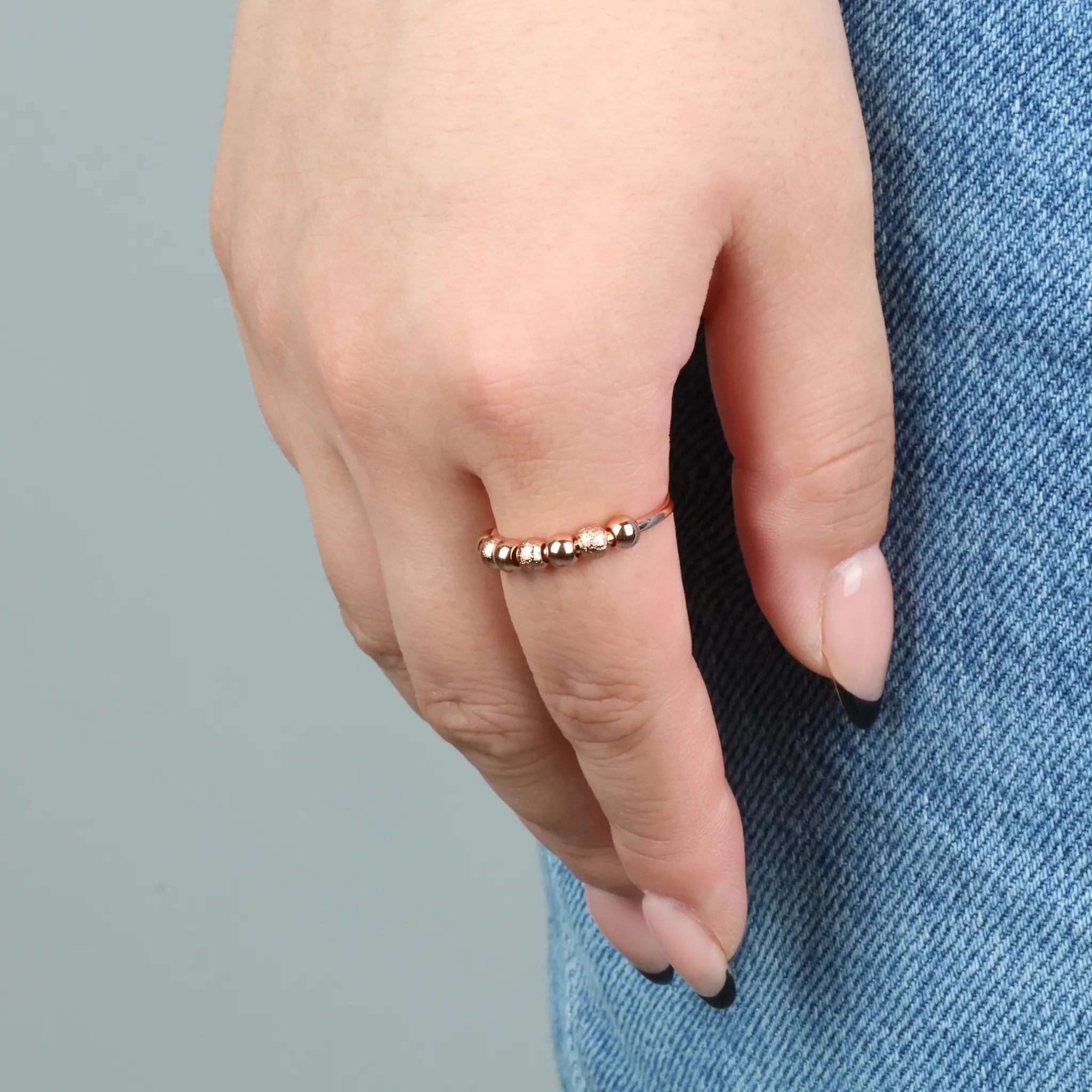 Roségouden Ivy Bead fidget ring met geribbelde kralen gedragen bij spijkerbroek – Luminora