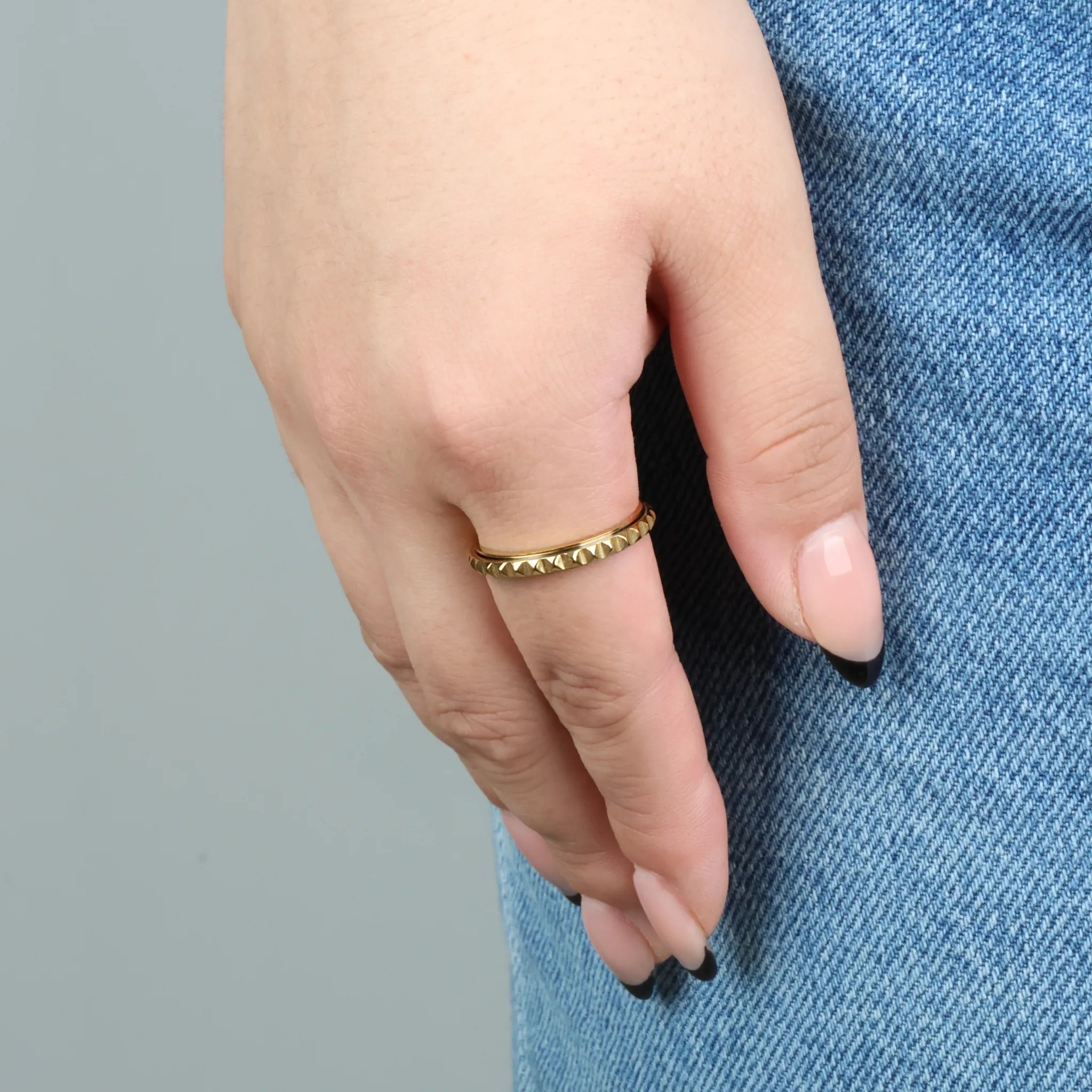Gouden Lumen fidget ring met studpatroon gedragen op spijkerbroek – Luminora