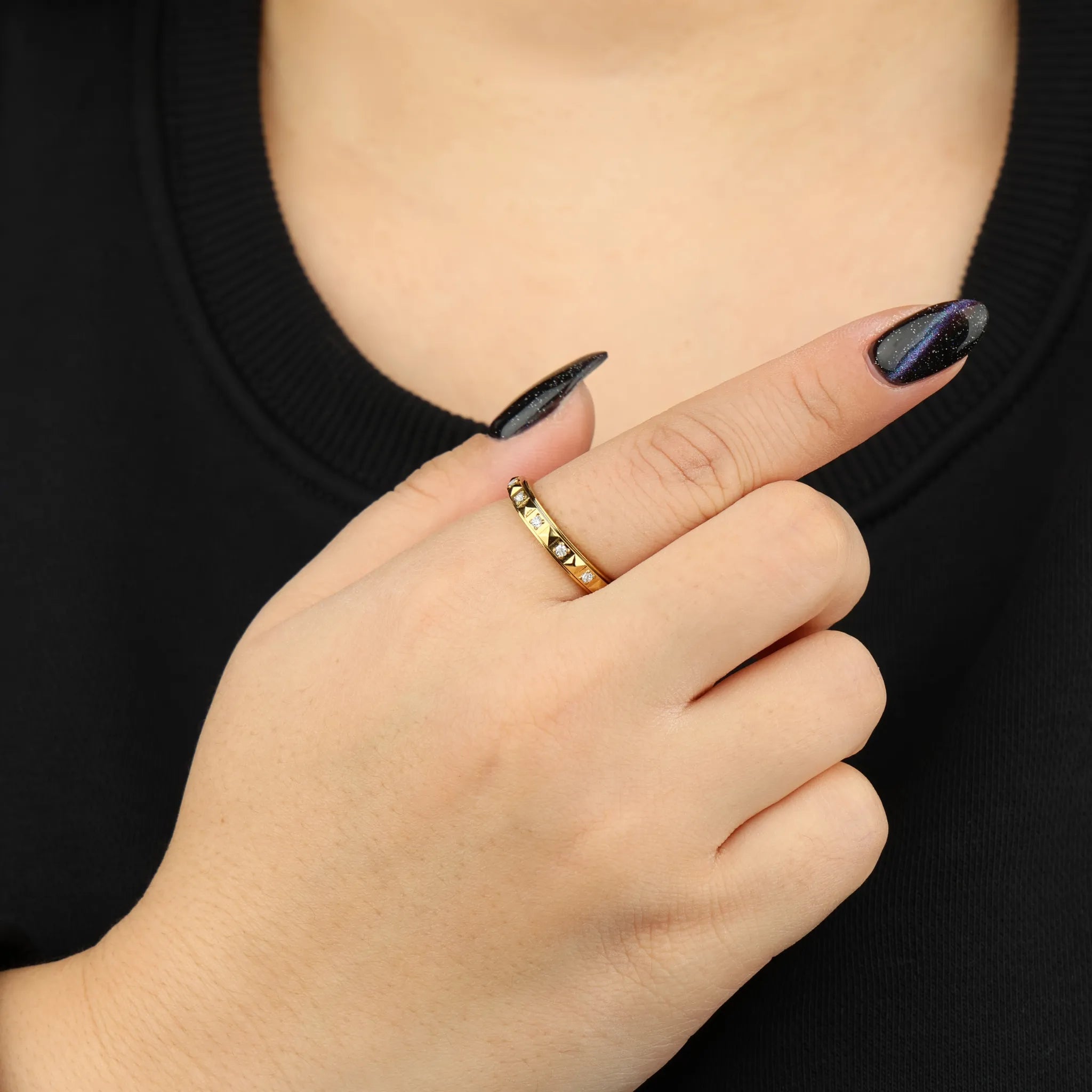 Gouden Lumi anxiety ring gedragen aan vrouwenhand voor borst met zwart shirt – Luminora