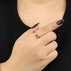 Gouden Lumi anxiety ring gedragen aan vrouwenhand voor borst met zwart shirt – Luminora