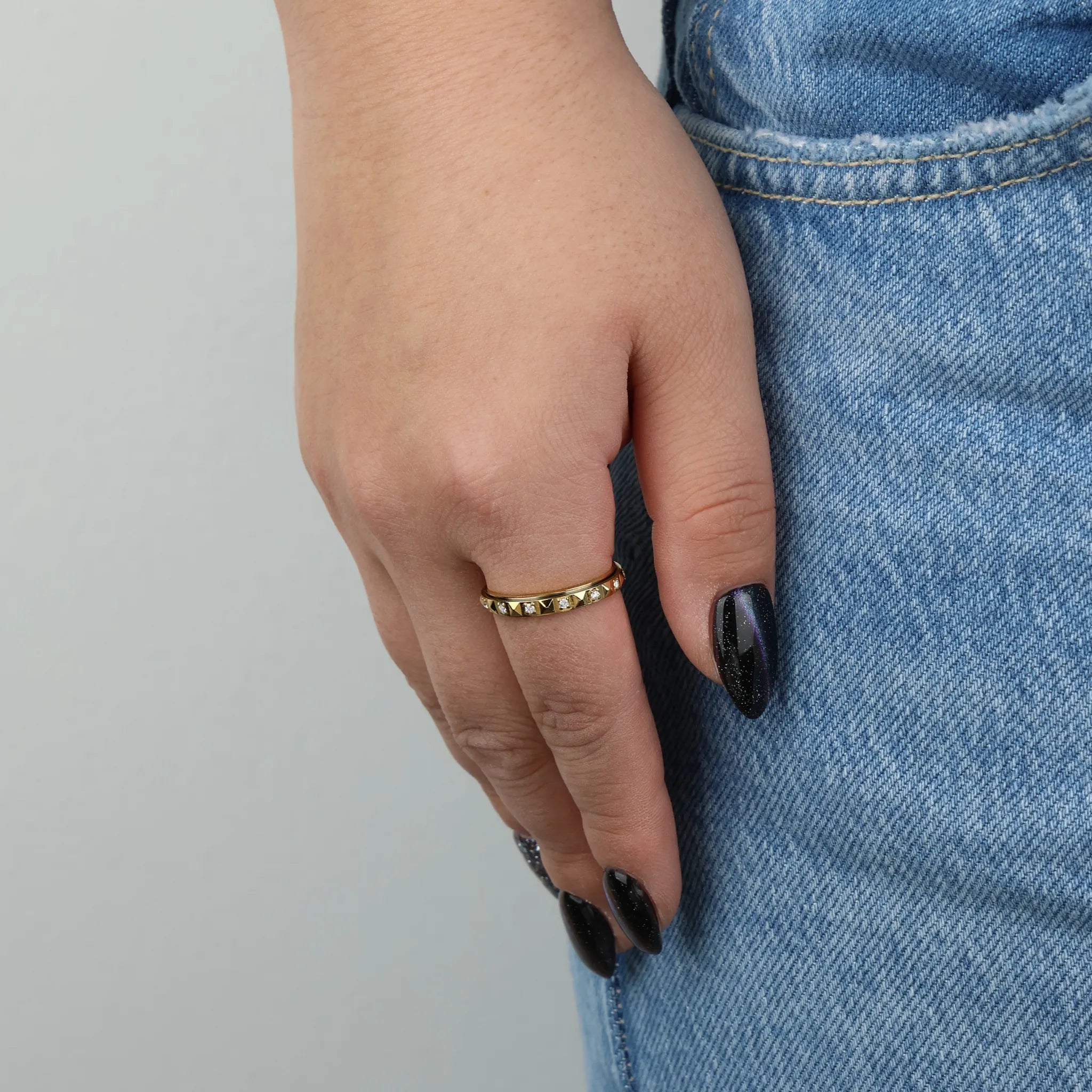 Gouden Lumi fidget ring gedragen aan vrouwenhand met spijkerbroek – Luminora