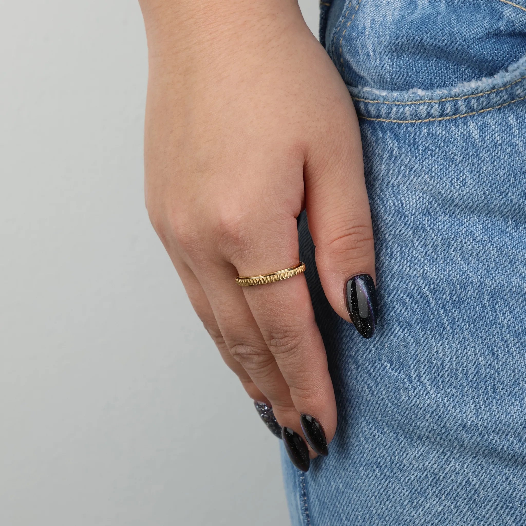 Gouden Mello fidget ring gedragen aan vrouwenhand met spijkerbroek – Luminora