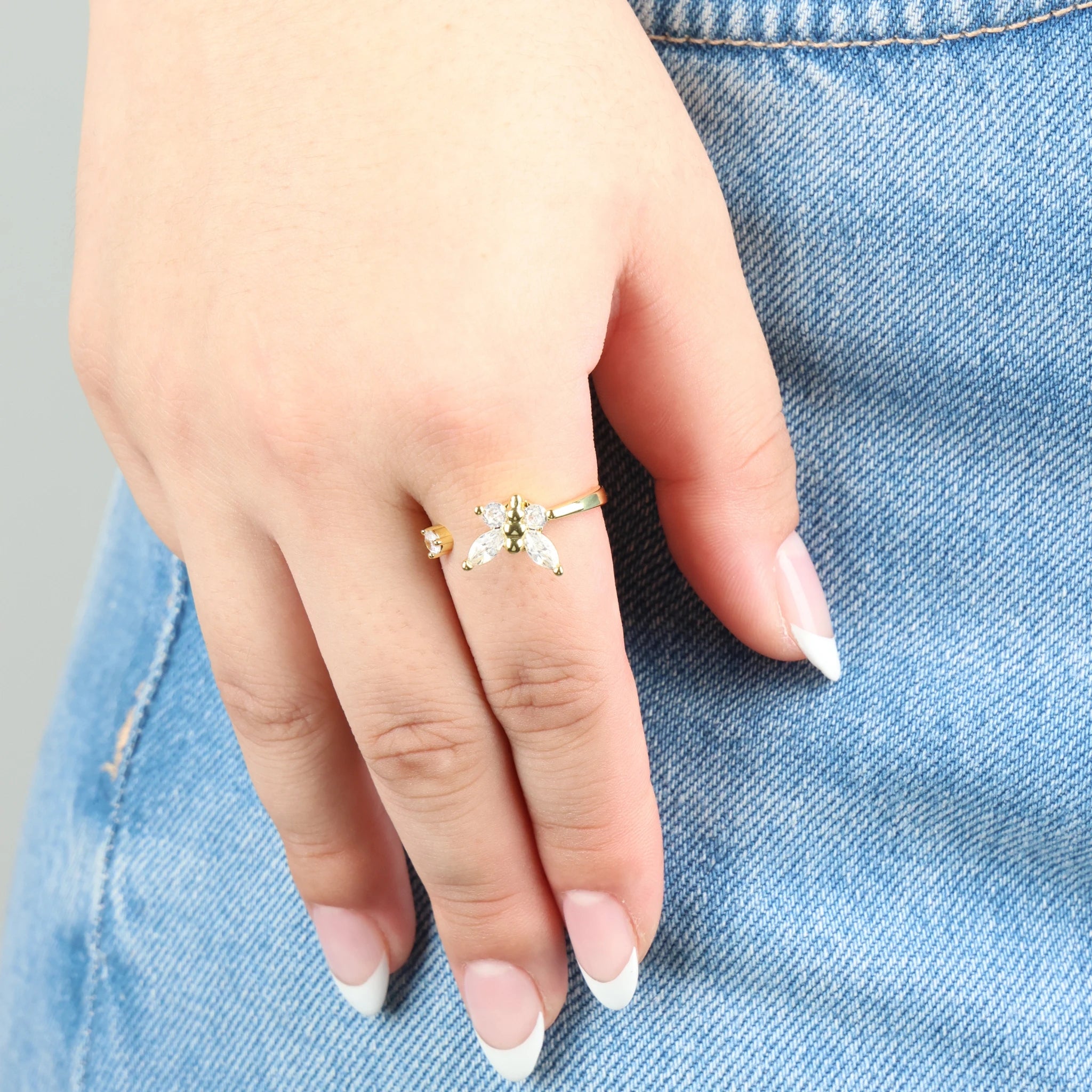 Draaiende gouden Nabi stress ring in de vorm van een vlinder, vastgelegd tegen een jeans achtergrond.