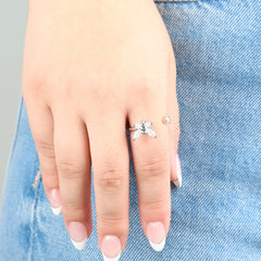 Close-up van de zilveren Nabi stress ring met vlinderontwerp gedragen op een jeans.